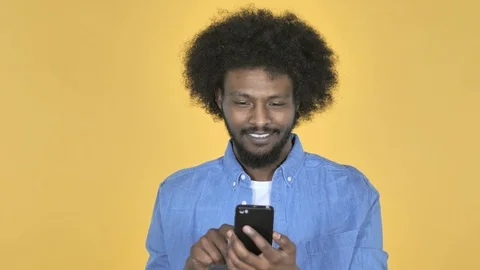 Afro-American Man Browsing Smartphone on Yellow Background Stock Footage 99222411