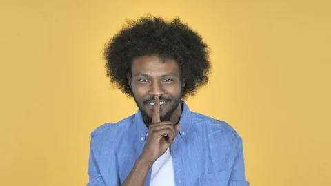 Afro-American Man Gesturing Silence, Finger on Lips, Yellow Background Video stock 99220469