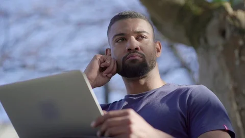 Afro-American man looking around, thinking, typing on laptop Video stock 105431906