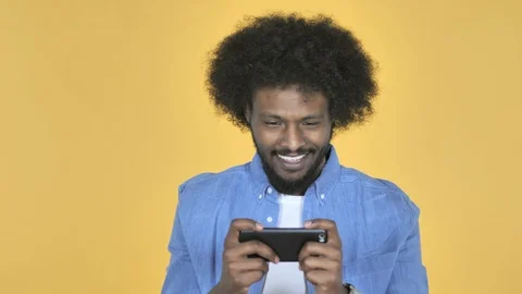 Afro-American Man Playing Game on Smartphone on Yellow Background Stock Footage 99222900