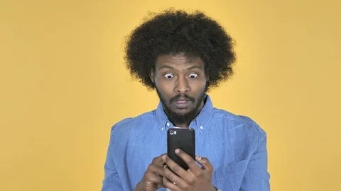 Afro-American Man in Shock while Using Smartphone on Yellow Background Stock Footage 99222510