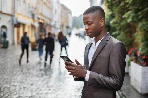 Afro american man in suit using smartphone on street Stock Photos