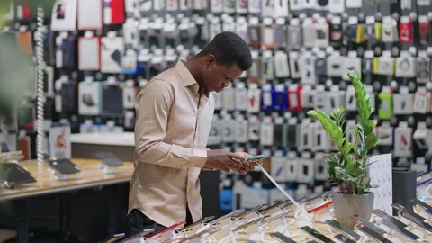 Afro-american man is testing different models of smartphones in digital Stock Footage 153132189