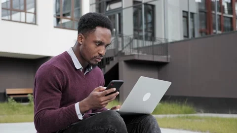 Afro American man using mobile phone for entering code on laptop. Stock Footage 161534277