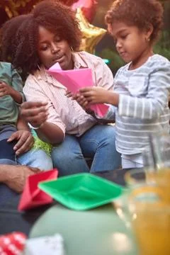 Afro-american mother teaching daughter how to make paper boat. Family value,  Stock Photos
