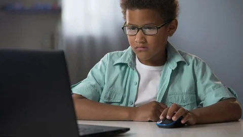 Afro-American nerd playing computer games instead of learning, child addiction Video stock 80691750