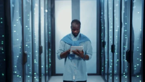 Afro-american smart IT worker holding digital tablet standing inside server Video stock 121159253