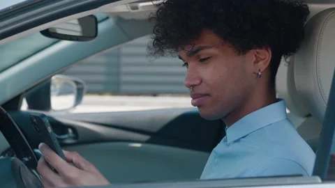 Afro-american student is using smartphone, sitting in car, communicating in Stock-Footage 158049946