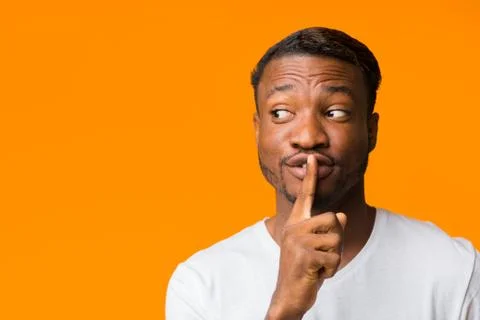 Afro Guy Gesturing Finger On Lips Standing Over Orange Background Stock Photos