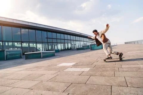 Afro guy rides fast on his skateboard over square Stock Photos