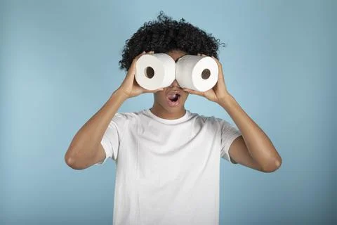 Afro-haired young man in basic white t-shirt looks astonishingly through toil Stock Photos