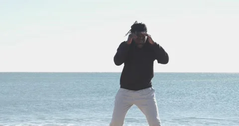 Afro man with dreadlocks training martial arts during winter on the beach Stock Footage 146951743