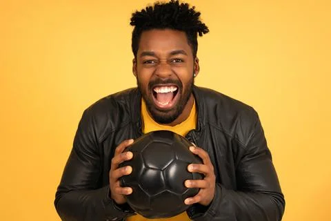 Afro man looking excited while holding a football ball. Stock Photos