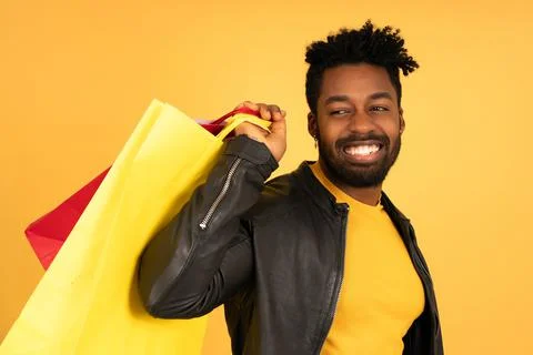 Afro man smiling while holding shopping bags. Stock Photos