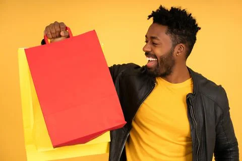 Afro man smiling while holding shopping bags. Stock Photos