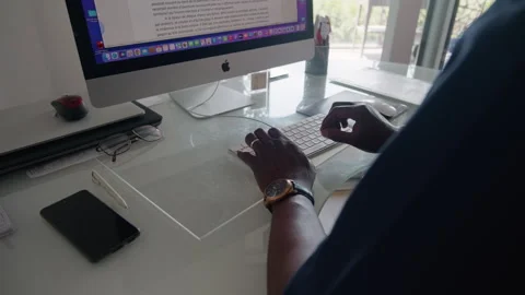 Afro man's hands writing on his computer, working on his desk Stock Footage 336529693