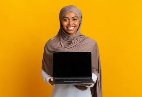 Afro Muslim Girl In Headscarf Holding Laptop Computer With Black Screen Stock Photos