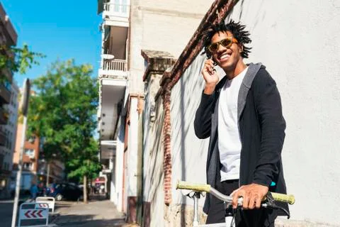 Afro young man using mobile phone and fixed gear bicycle. Stock Photos