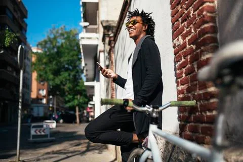 Afro young man using mobile phone and fixed gear bicycle. Stock Photos