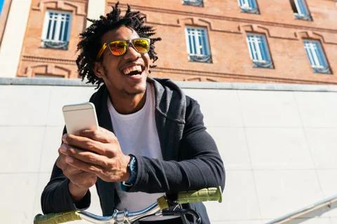 Afro young man using mobile phone and fixed gear bicycle. Stock Photos