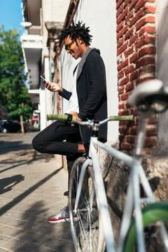 Afro young man using mobile phone and fixed gear bicycle.x Stock Photos