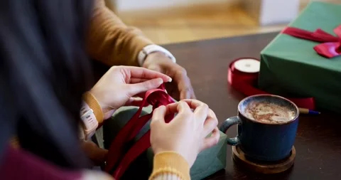 After arranging red ribbon loops, two hands are tying Christmas gift bow at Stock Footage 344228102