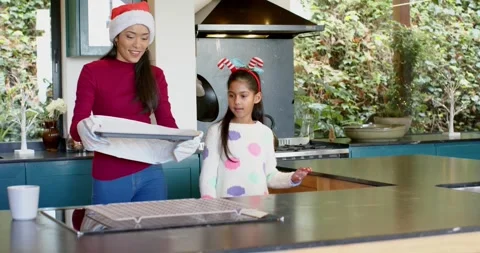 After baking, Diverse mother with oven mitts and daughter unveiling cookie tray Stock Footage 344221803