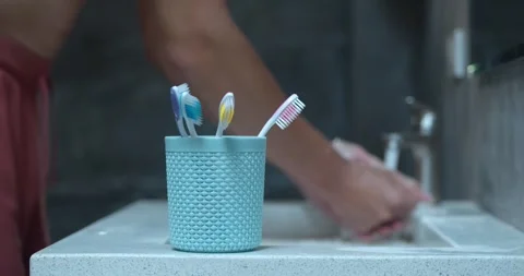 After brushing teeth person washes hands under water completing hygiene routine Stock Footage 264743642