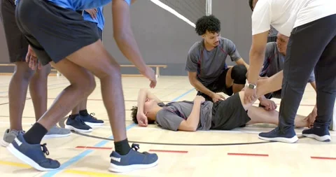 After collapse, teammates pausing on gym court rushing to Asian player testing Stock Footage 341664687