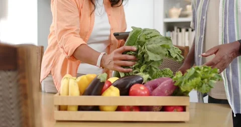 After crate arrival, senior couple unpacking and inspecting produce at kitchen Stock Footage 344949667