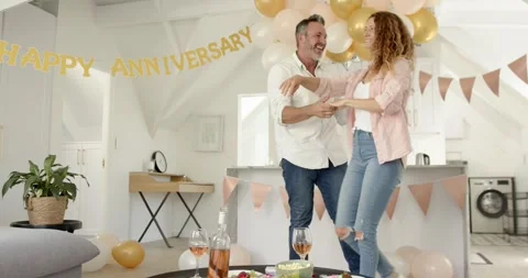 After embracing, senior couple dancing at kitchen island celebrating anniversary 스톡 동영상 316967834