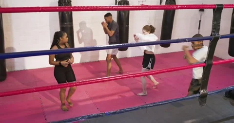 After entering red ring, diverse boxing coach and trainees practicing jab Stock Footage 344333095