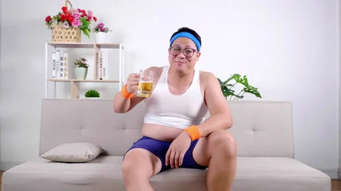 After exercise  a fat man shows his belly on the sofa Video stock 153068944