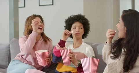 After first kernel toss by friend, diverse friends tossing popcorn kernels into Stock Footage 337704963