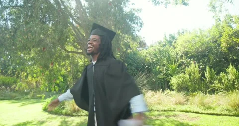 After graduating man in black gown raising rolled diploma ribbon, waving cap, Stock Footage 344327904