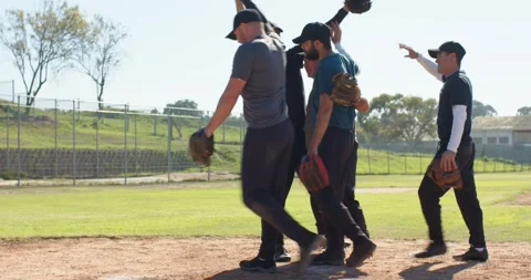 After inning five male baseball teammates walking across baseline tapping gloves Stock Footage 339413069