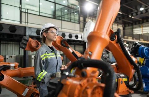 After installing a program on the robotic arm, a female engineer with a ro... Stock-Fotos