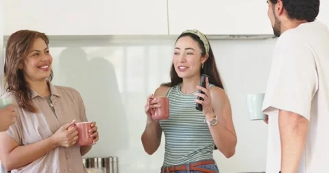 After laughter friends chatting in kitchen with mugs and smartphone as center Stock Footage 342019695