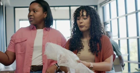 After package arrival African American women opening bubble wrap on table near Stock Footage 336059028