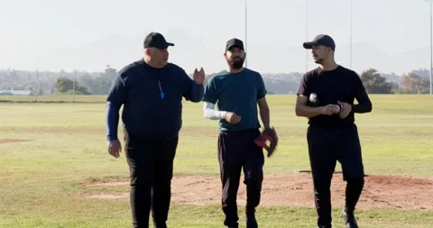 After reaching pitcher's mound, baseball coach with two male players correcting Stock Footage 341735951
