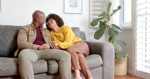 After sitting, diverse couple leaning in, talking, linking hands, sharing coffee Stock Footage 340009724