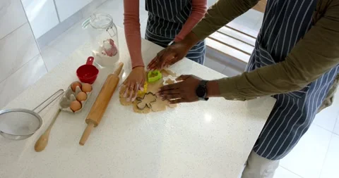 After smoothing cookie dough, man and woman are cutting star shapes in home Stock Footage 340773061