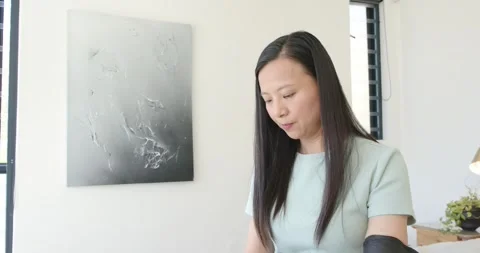 After spotting rolled document, Asian woman scanning white pages at home with Stock Footage 336716144
