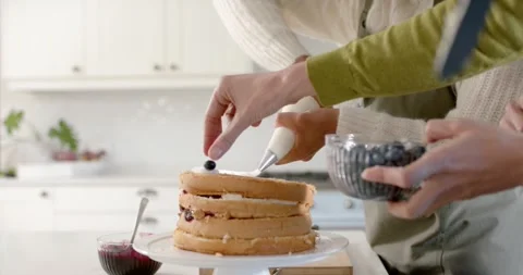 After stacking, two bakers are placing blueberries on three-layer cake to Stock Footage 347307445