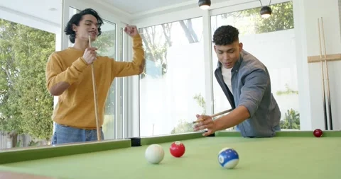 After striking cue ball on pool table, male friends celebrating success with Stock Footage 345071209
