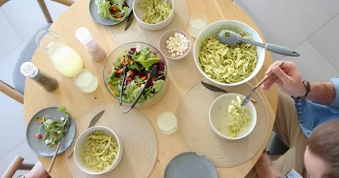 After table set, round table is showing green pasta, salad as right diner is Stock Footage 335986900