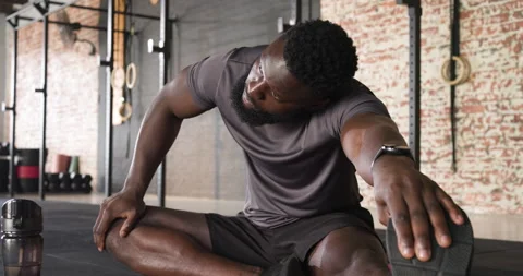 After workout man rolling massage ball under calf stretching hamstring on red Stock Footage 314043397