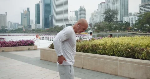After workout public park man in pain clutching back discomfort back injury Stock Footage 274429105