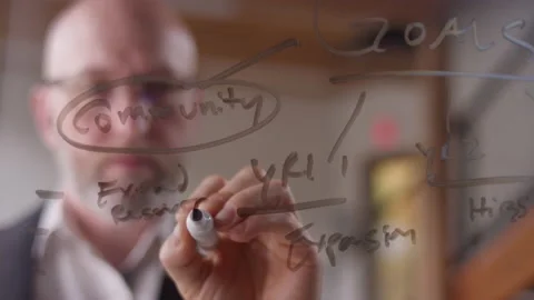 After writing plans on clear plexiglass, a modern businessman reviews his work Video stock 133269161