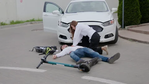 In aftermath of accident driver of scooter lies injured on ground woman driver Stock Footage 272452913